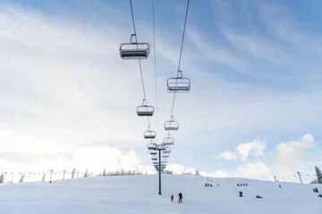 Schilderijen op glas beautiful ski lift over snow mountain in ski resort with blue sky background. © checubus