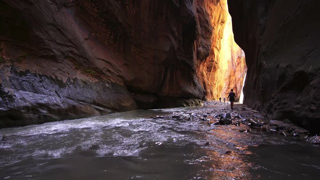 Woman hiking through a slot canyon in Zion National Park