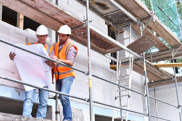 Architekten/ Bauleitung auf einer Baustelle beim Neubau eines Hauses auf dem Baugerüst