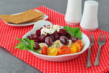 Easy breakfast : beetroots, cherry tomato, egg, cottage cheese and crisps in a white plate on a red textile background. Healthy food concept.