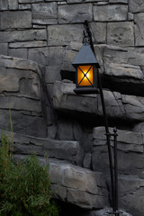 Mystical image of an old lantern at a stone wall.