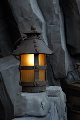 Mystical image of an old lantern at a stone wall.