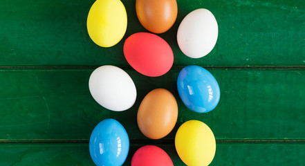 Fototapeta na wymiar Colored eggs in nest on wooden background, selective focus image. Happy Easter Card - space for text 