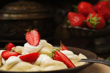 Delicious dumplings with fresh strawberries served with whipped cream and sugar.