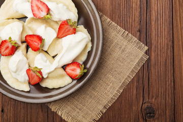 Delicious dumplings with fresh strawberries served with whipped cream and sugar.