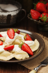 Delicious dumplings with fresh strawberries served with whipped cream and sugar.