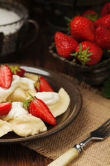 Delicious dumplings with fresh strawberries served with whipped cream and sugar.