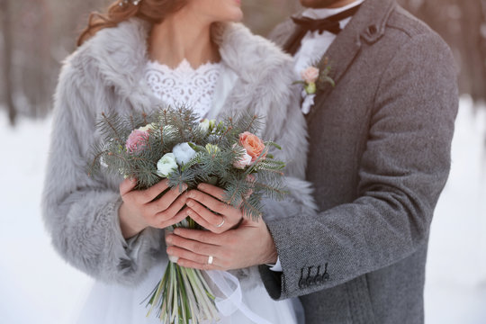 Happy wedding couple with bouquet outdoors on winter day, closeup