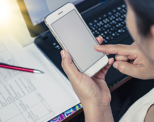 Woman working at office desk and texting with her mobile phone