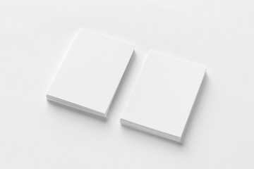 Mockup of two vertical business cards at white textured paper background.