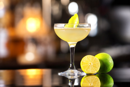Closeup image of daiquiri cocktail decorated with lemon at bar counter background.