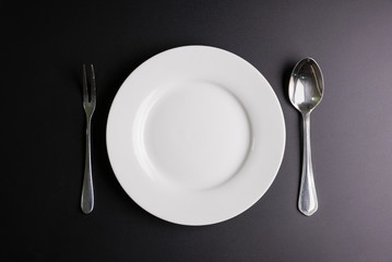 White dish, Spoon and fork isolated on black background with copy space image for your text.