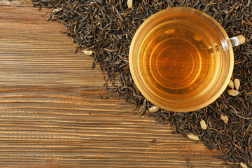 Fototapety  Suszone liście herbaty i filiżanka aromatycznego napoju na drewnianym tle