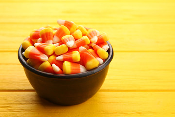 Bowl with tasty Halloween candies on wooden background