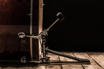 Fototapeta na wymiar percussion instrument, bass drum with pedal on wooden boards with a black background