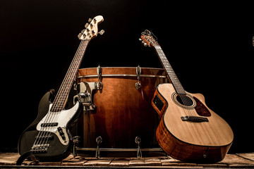 musical instruments, bass drum barrel acoustic guitar and bass guitar on a black background - obrazy, fototapety, plakaty