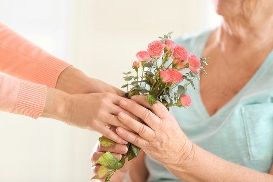 Female Hands Giving Flowers To Old Woman