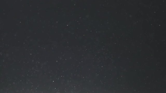 Slow motion of dust particles with light flare from below fly in the air loopable, 180fps prores footage