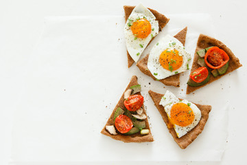 Slices of pie similar to pizza with vegetables, egg and avocado lie on white background, top view. - Powered by Adobe