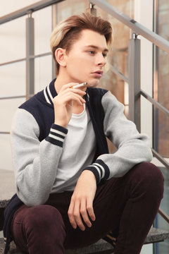 Teenage boy sitting on stairs and smoking