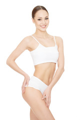 Fototapeta premium Perfect figure. Gorgeous young happy woman posing at the studio feeling her silky skin touching her upper leg looking to the camera on white background.