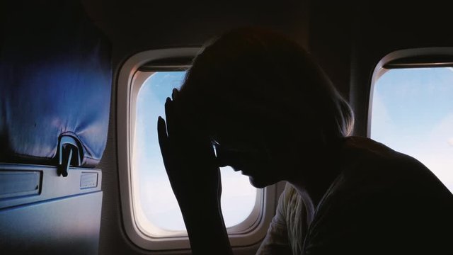 Anxiety and experience in flight. Silhouette of a young woman in an airplane, afraid to fly