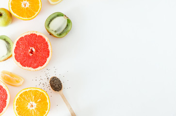 Whole and half citrus fruits and apples lie on a white background.