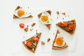 Slices of pie similar to pizza with vegetables, egg and avocado lie on white background, top view. - Powered by Adobe