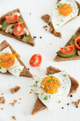 Slices of pie similar to pizza with vegetables, egg and avocado lie on white background, top view.