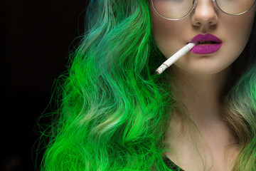 Fierce lady. Cropped closeup of a green haired female fashion model wearing purple lipstick holding...