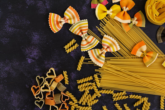 Dry pasta background. Different pasta on dark background. Flat lay. Top view.