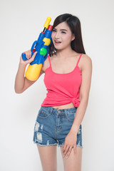 Thailand New year concept. Focus on toy gun. Young happy beauty Asian woman holding plastic water gun at Songkran festival, Thailand. Isolated on white background.