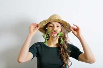 Cheerful young woman in a hat fooling around with parsley, healthy life