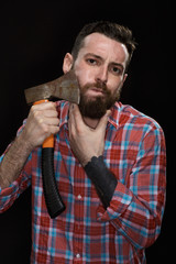 Wild and manly. Shot of an attractive bearded male shaving his face with an axe holding his chin on black background at the studio.