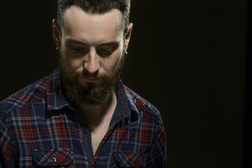 Power in calm. Cropped studio shot of a bearded handsome man looking down thoughtfully copyspace on the side on black background.
