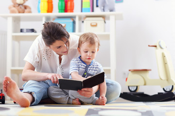 Happy mother playing with baby boy at home