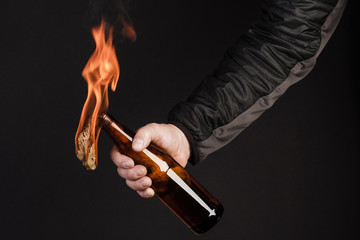 Glass bottle, the so-called Molotov cocktail in the hand of the activist. Isolated on a black...