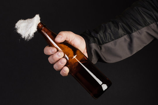 Glass bottle, the so-called Molotov cocktail in the hand of the activist. Isolated on a black background.