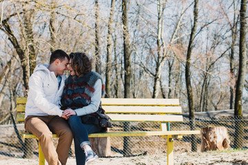 Happy couple in love hugging and sharing emotions, holding hands on a bench by the river