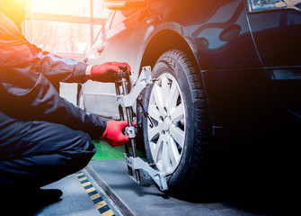 Car mechanic installing sensor during suspension adjustment.