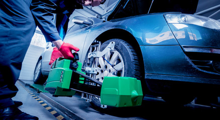 Car mechanic installing sensor during suspension adjustment.