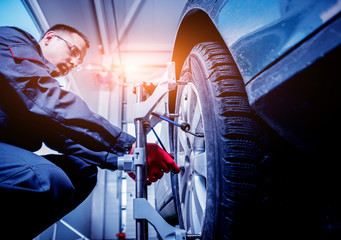 Car mechanic installing sensor during suspension adjustment.