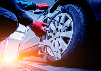 Car mechanic installing sensor during suspension adjustment.