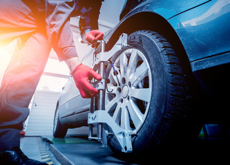 Car mechanic installing sensor during suspension adjustment.