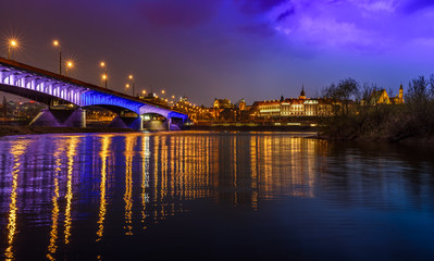 Fototapeta na wymiar Zamek Królewski - Royal Castle in Warsaw, with a bridge and river reflection as seen by night