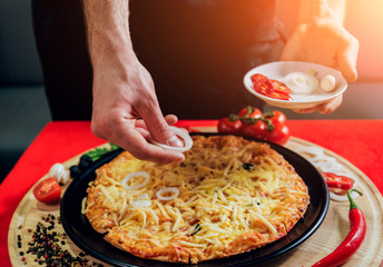 The cook is making pizza. Adds the ingredients.