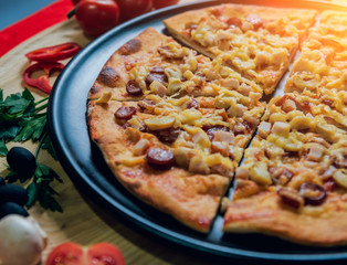 Large hot pizza on the black plate.