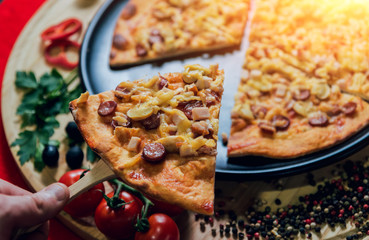 A slice of pizza in his hand. A restaurant.