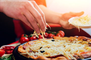 The cook is making pizza. Adds the ingredients.