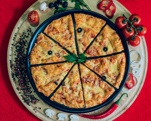 Large hot pizza on the black plate.